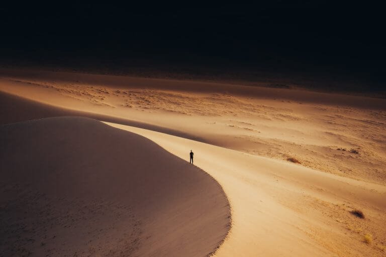 Un homme seul qui marche sur la crête d'une dune, dans le desert