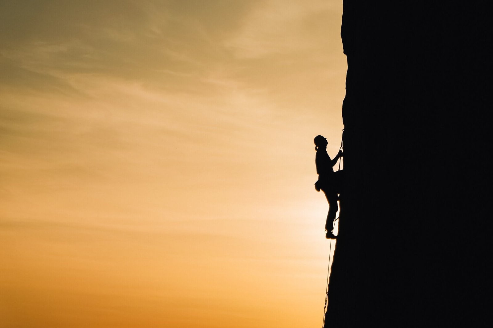 une alpiniste sur une pente raide, symbole de courage